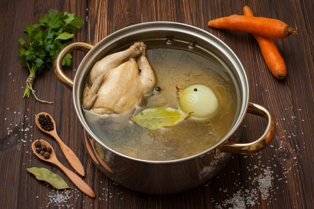 Close up of chicken broth being made surrounded by its ingredients.  Chicken broth makes a great beef broth substitute