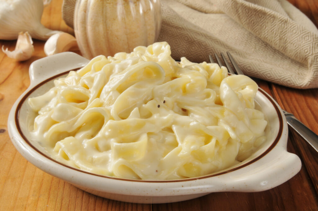 Close up of creamy Alfredo sauce on pasta.