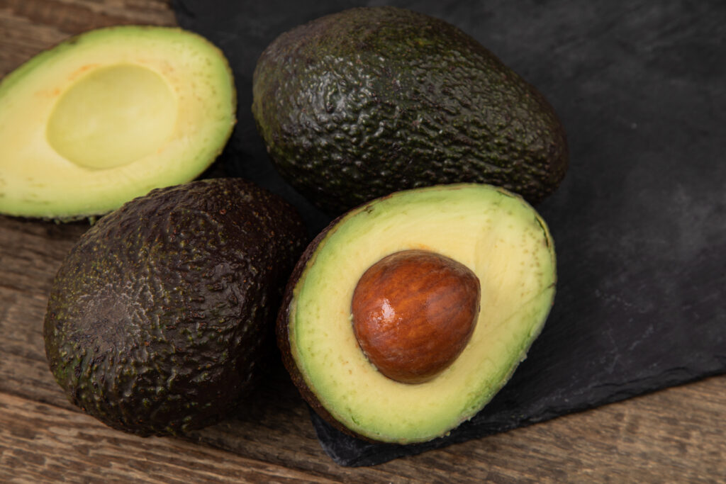 Three avocados with one cut in half.  Once ripe, avocados can last in the fridge uncut for two or three days