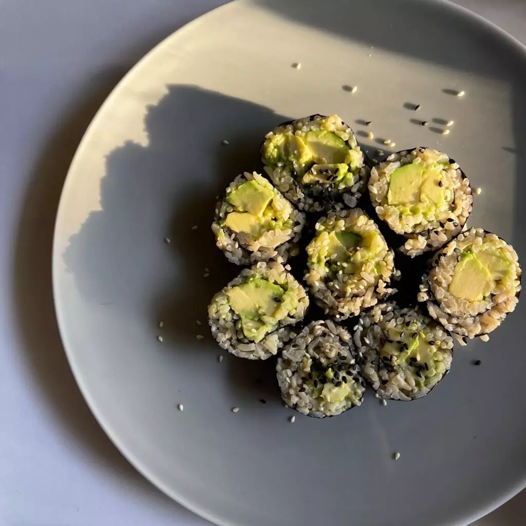 Avocado rolls arranged on a grey plate and garnished with sesame seeds.  Avocado rolls are a great vegetarian sushi option. 