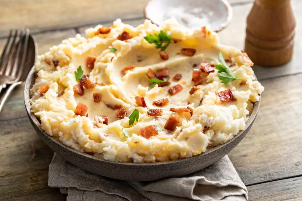 Mashed potatotes in a bowl with butter and topped with bacon bits and parsley.  It is easy to freeze mashed potatoes if you have the proper containers.  