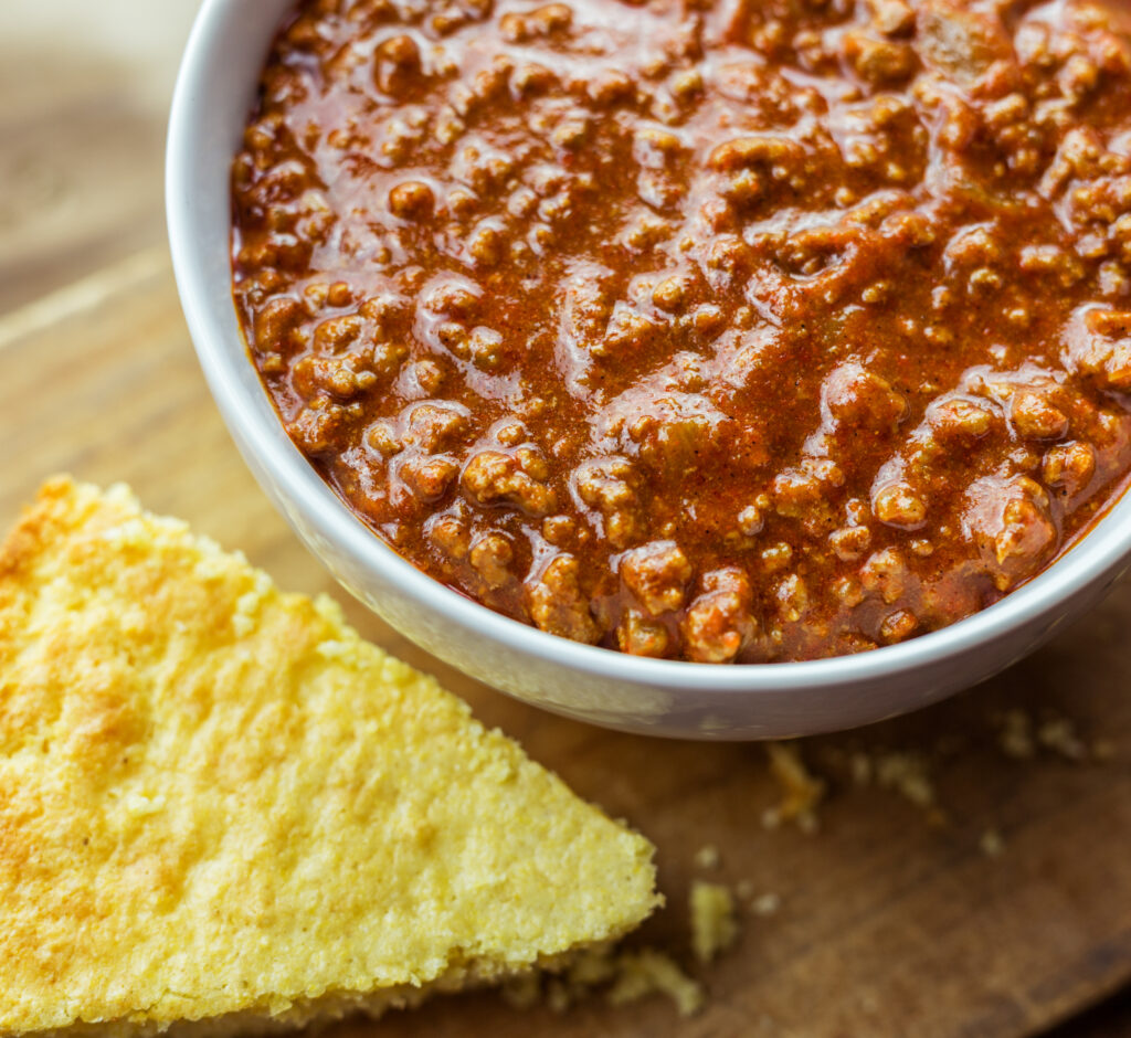 Close up bowl of chili with wedge of cornbread.  Chili is only good at room temperature for a maximum of two hours.