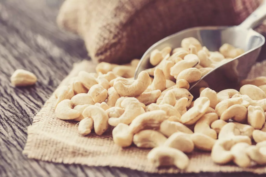 Close up of cashews in a scoop on a cloth.  Like peanuts, cashews work as a chickpea alternative in snacks.  However, they can also be soaked and pureed and used in dips