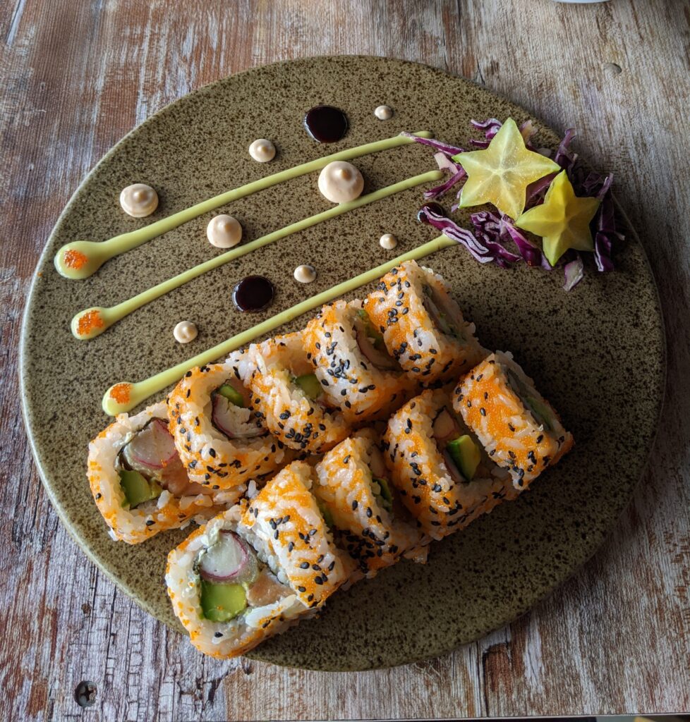 Various cooked sushi rolls on tray with ginger, wasabi and Japanese mayo