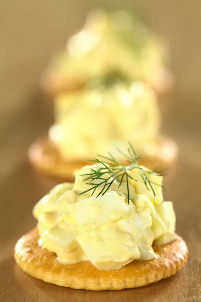 Egg salad served on a cracker garnished with dill