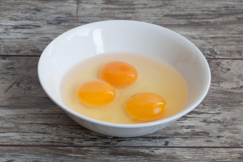 Three egg yolks in a bowl.  Adding egg yolk not only thickens spaghetti sauce but also adds a creamy texture.
