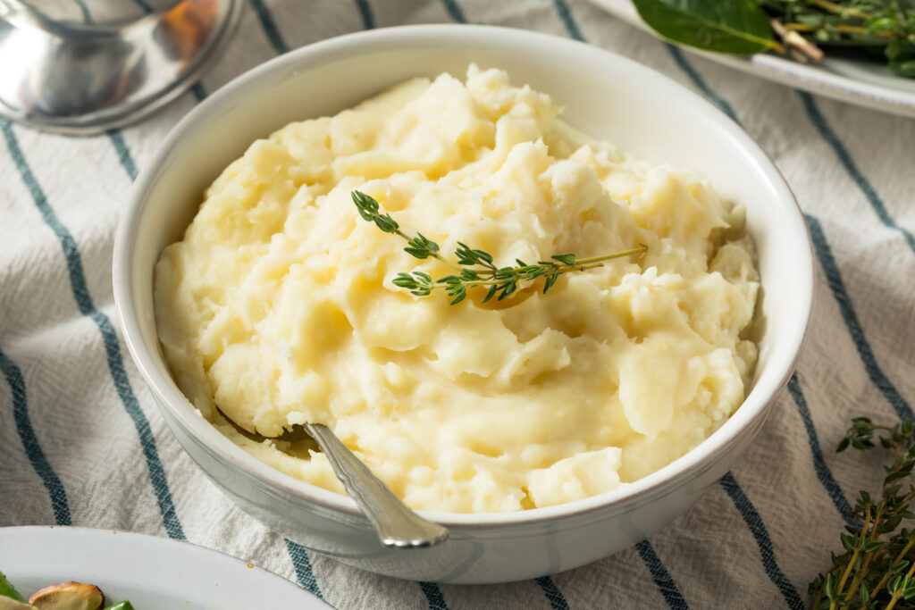 Mashed potatoes in a bowl with a sprig of thyme.  While not an obvious choice, mashed potatoes are an effective way to thicken spaghetti sauce. 