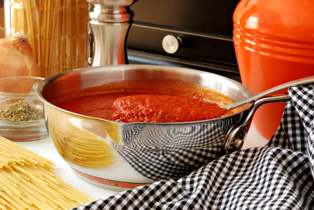 Pasta sauce in a pan with herbs and spaghetti in the background.  Depending on the type of sauce, spaghetti sauce can usually last from 3 to 7 days in the fridge.  