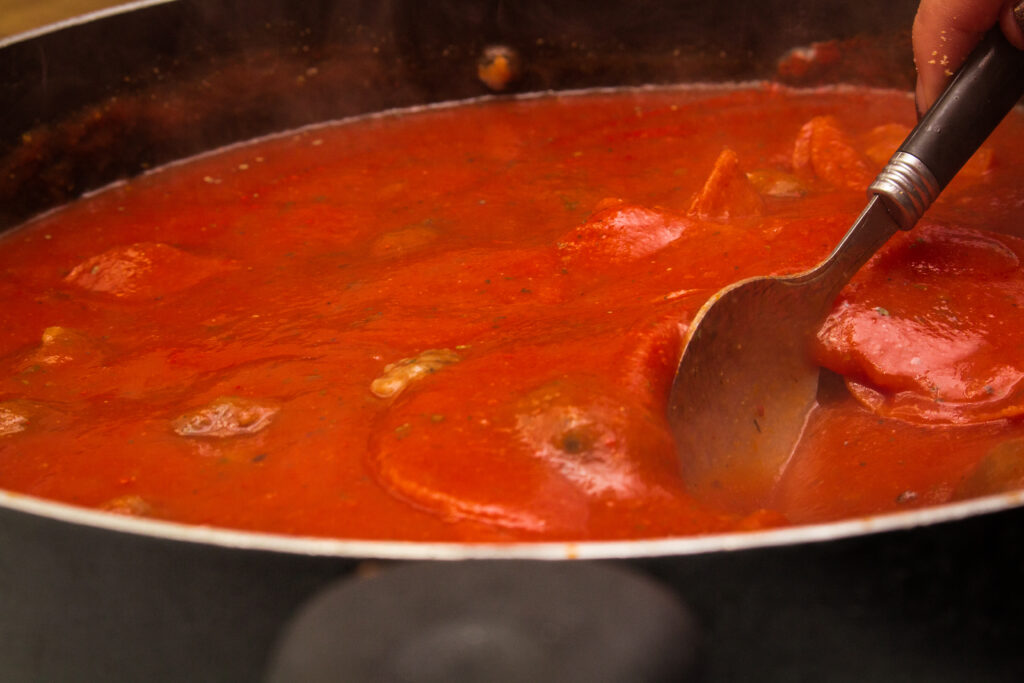 Red pasta sauce simmering in a pot.  Simmering is a great way to thicken spaghetti sauce by cooking out the moisture