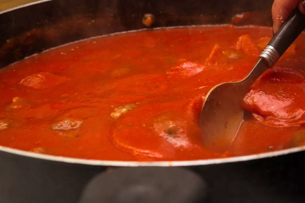 Red pasta sauce simmering in a pot.  Simmering is a great way to thicken spaghetti sauce by cooking out the moisture