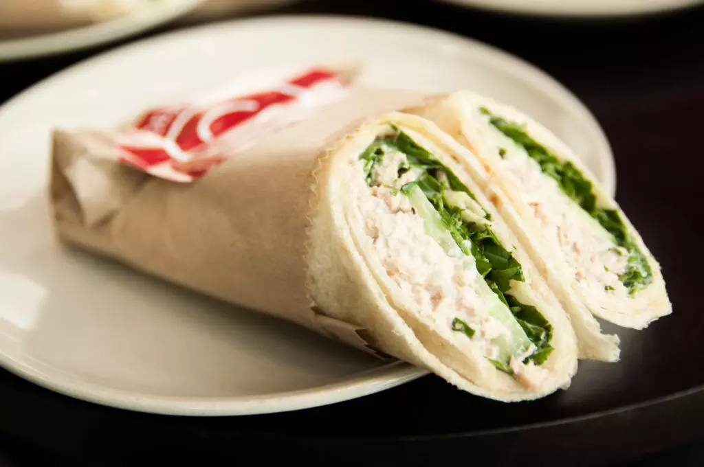 Tuna salad wrap on a white plate.  A good way to tell if tuna salad has gone bad is by using your senses, in particular, appearance, smell and taste.
