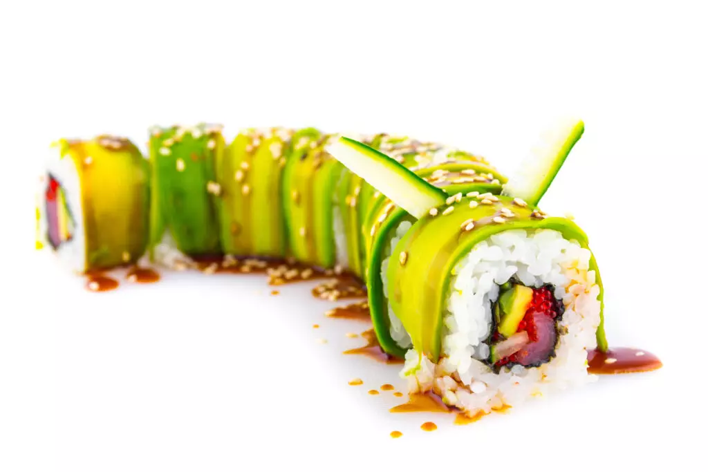 Close up of dragon rolls arranged with cucumber slices sticking out of them in the shape of antenna.