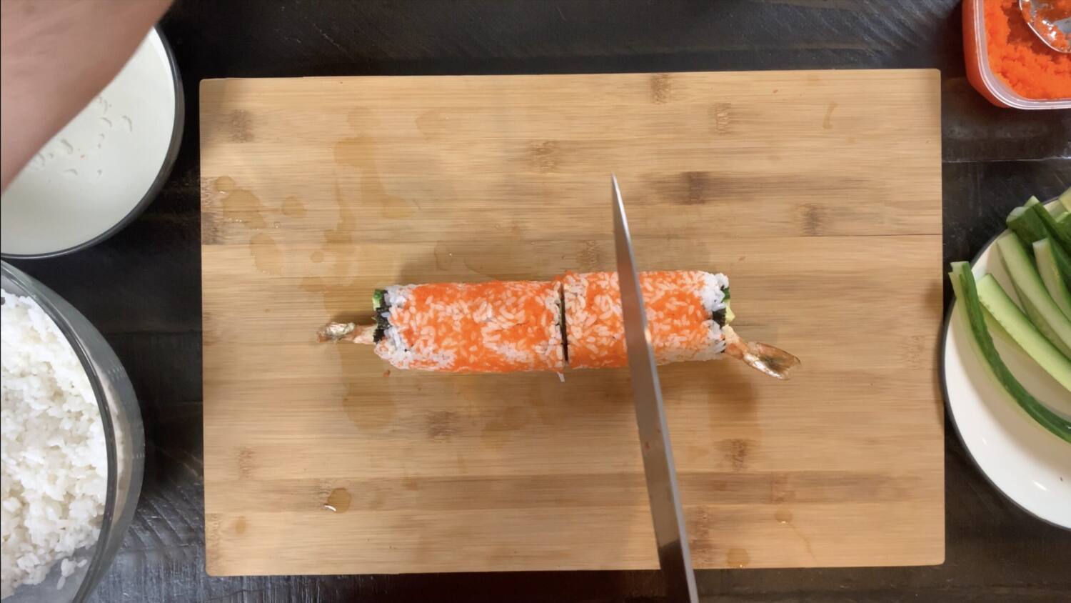 Using a wet, sharp knife, cut the shrimp tempura roll.