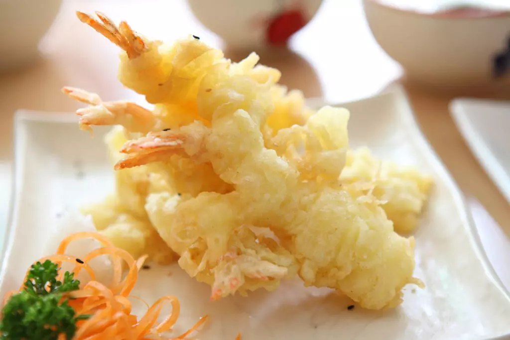 Shrimp tempura garnished with carrots shavings and parsley