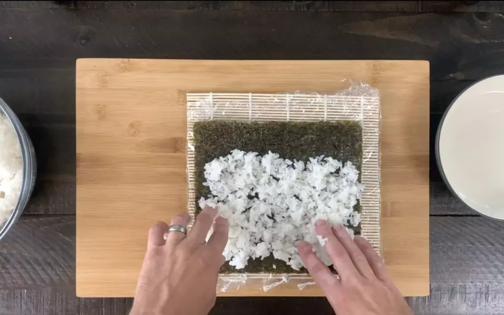 Pressing sushi rice to the nori sheet