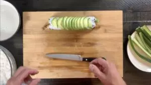 Adding avocado slices to the top of the dragon roll