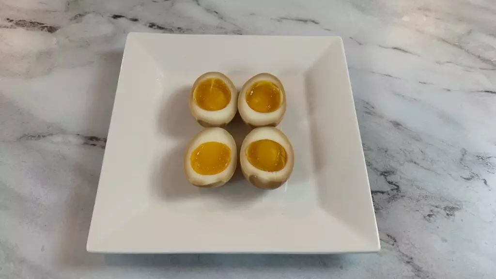Ramen eggs (ajitsuke tamago) cut in half and arranged on a white plate. 