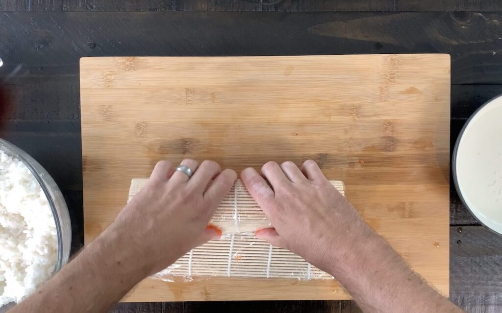 Rolling the Boston roll with a bamboo sushi mat.