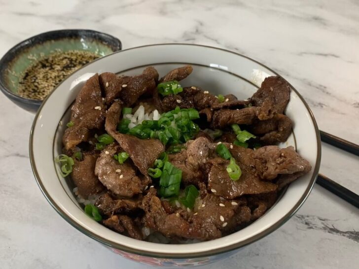 Yakiniku beef in a donburi bowl with scallions and Yakiniku sauce in a dipping bowl