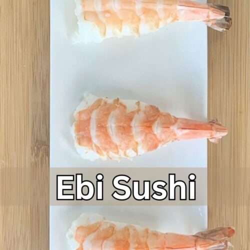 Close up shot of ebi sushi (shrimp sushi) on a white plate with a bamboo cutting board