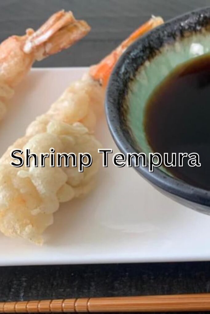 Shrimp Tempura on a white plate with tempura dipping sauce (tentsuyu) and a chopstick in the background