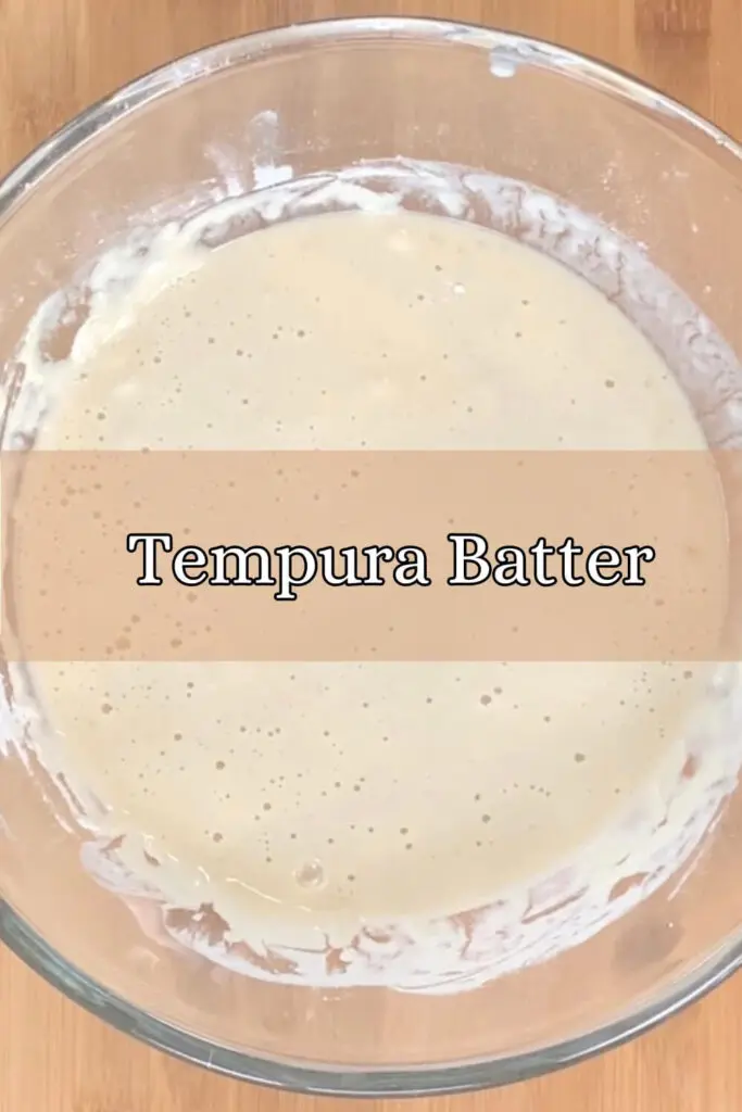 Tempura batter in a mixing bowl on a bamboo cutting board