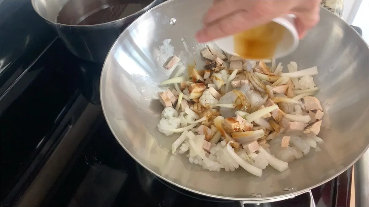 Add onions, squid, chashu, and shrimp to the wok and cook until the seafood is cooked. 
