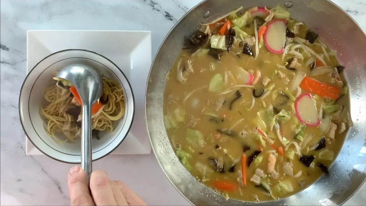 Add champon broth and toppings to the noodles in the bowl.