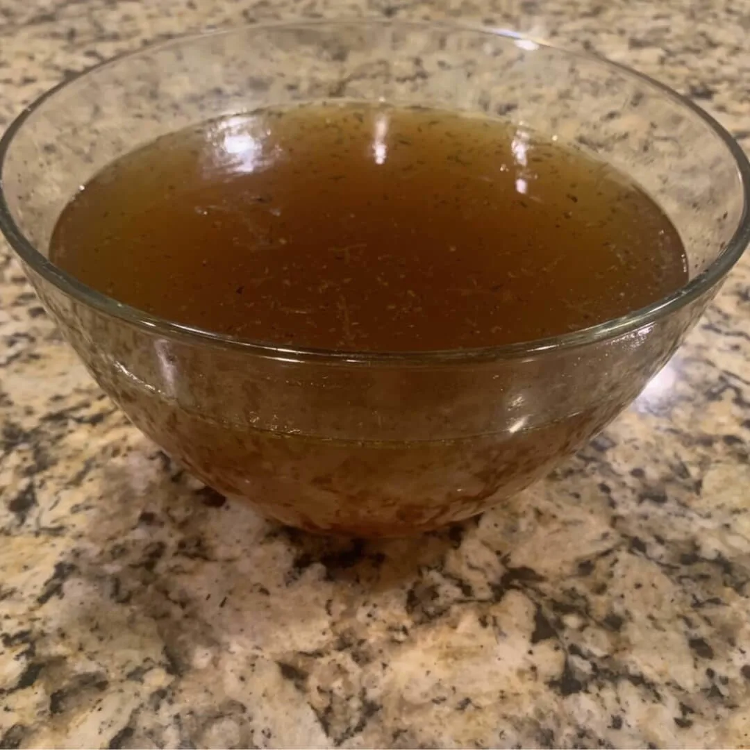 Homemade beef broth in a mixing bowl.