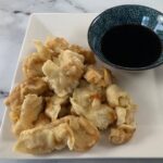 Chicken tempura on a white square plate with tempura dipping sauce in a Japanese ramekin.