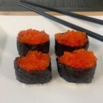 Ikura sushi on a white plate with chopsticks. Square photo for recipe.