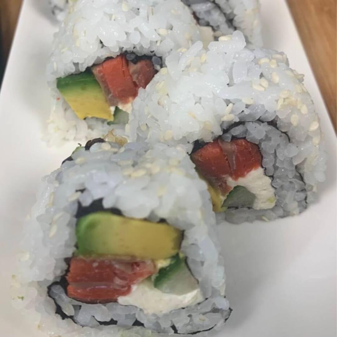 Close up Philadelphia rolls on a white sushi platter.