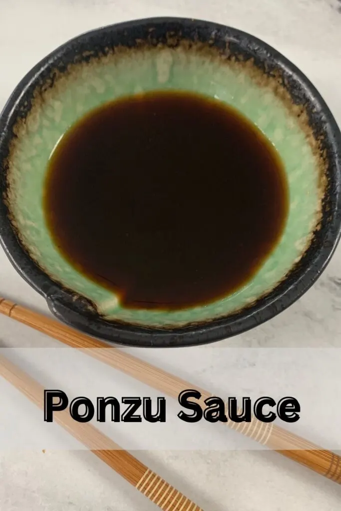 Vertical shot of ponzu sauce in a Japanese ramekin with choptsticks in the background.