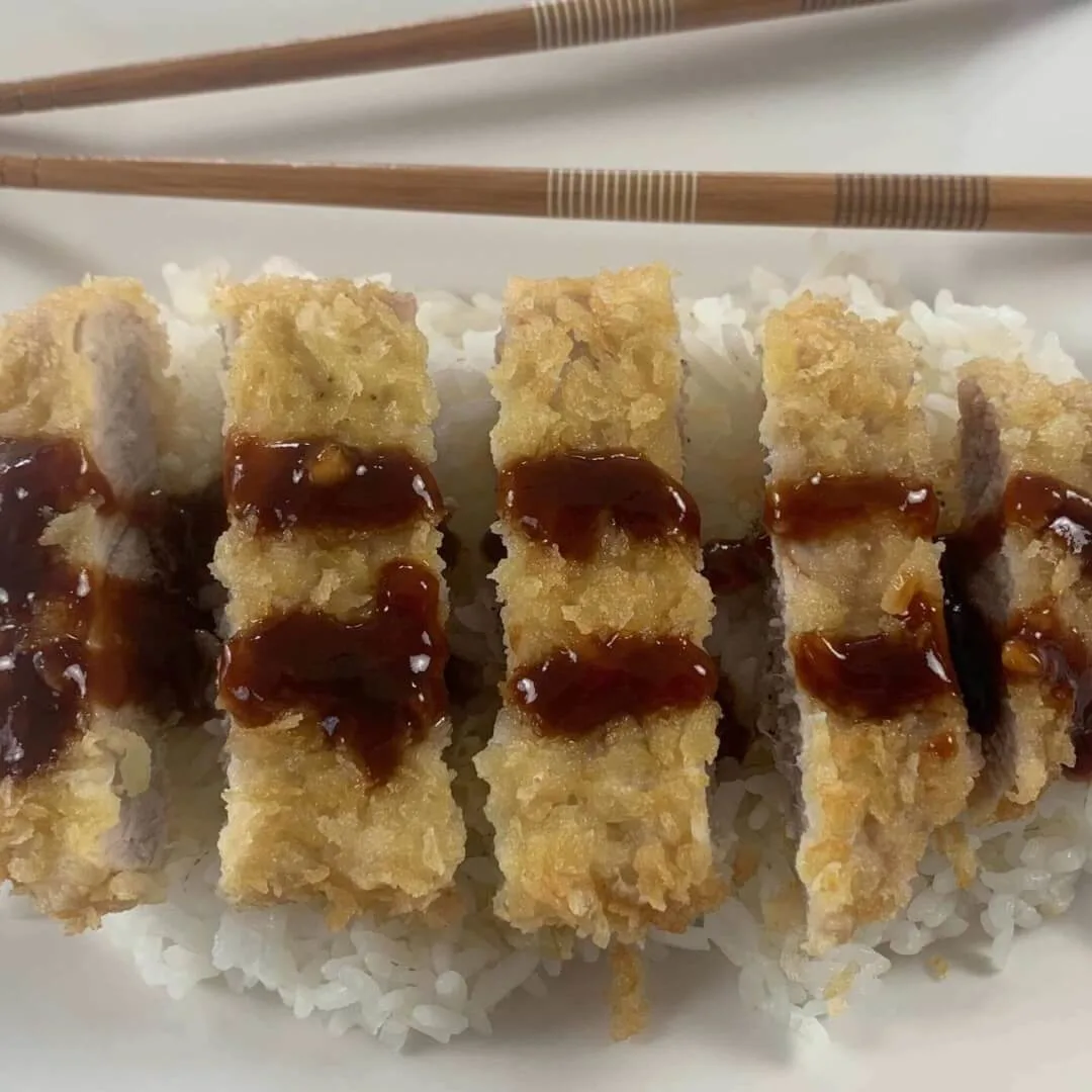 Tonkatsu close up square pic with katsu sauce drizzled on it and chopsticks in the background