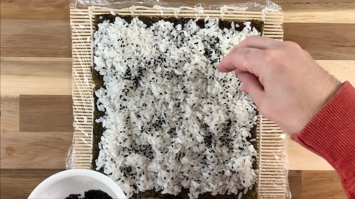 Then add black sesame seeds to the rice.  This helps the roll to pop visually and gives the spider roll some texture when eating. 