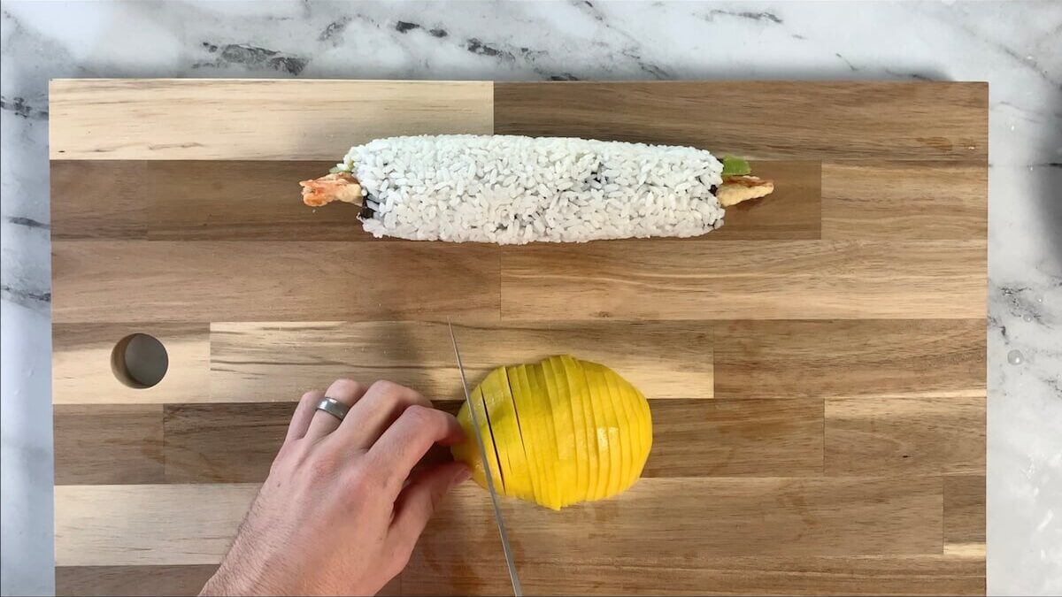 Slice the mango section into thin slices to be placed over the top of the mango roll.