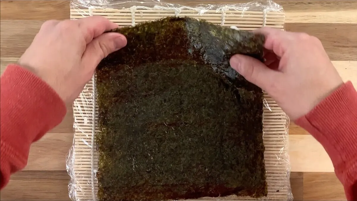 Flip the nori sheet to add fillings to the spider roll. 