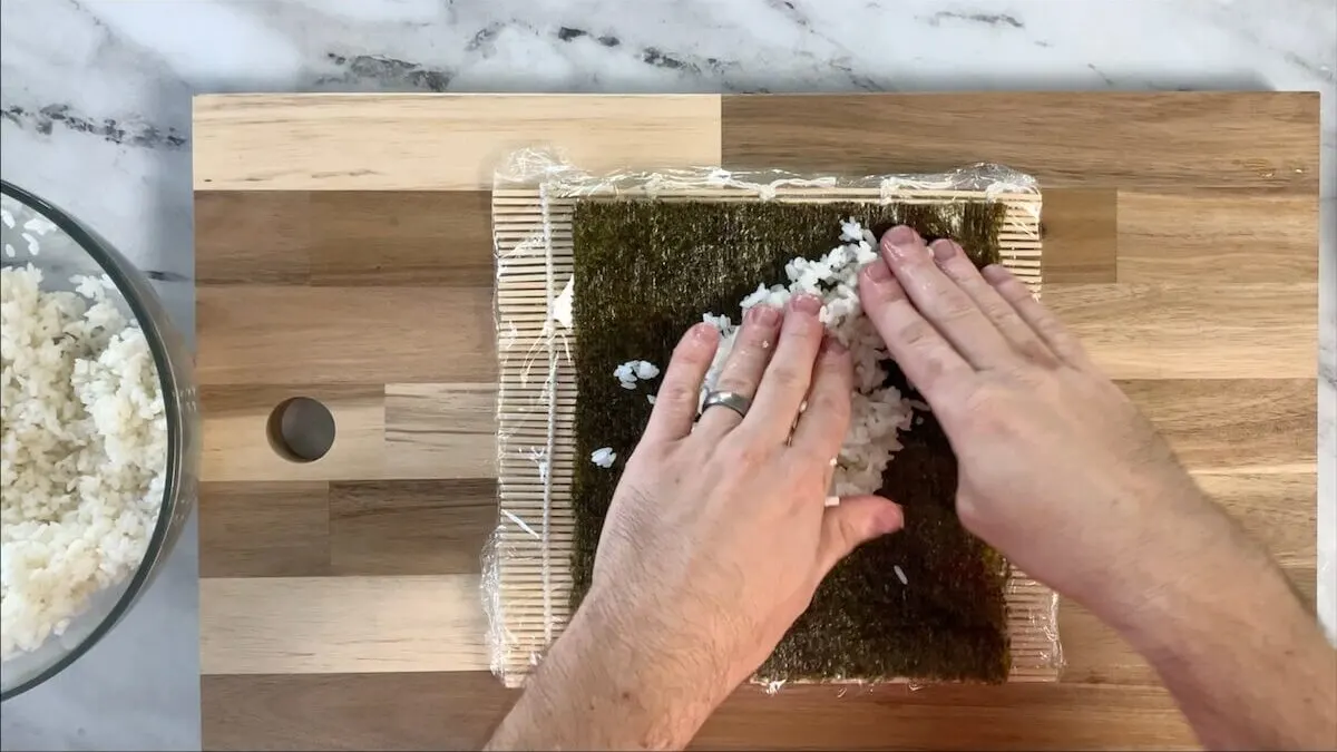 Press sushi rice onto the nori sheet.