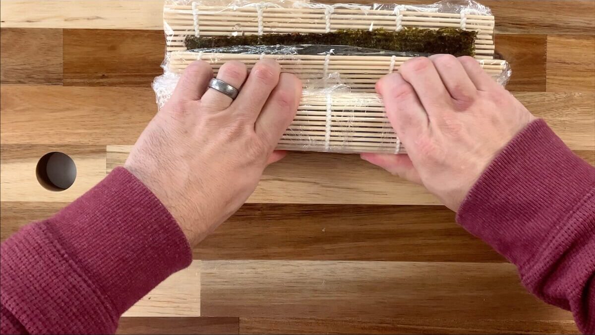Using a bamboo sushi mat, roll the vegetable roll sushi. 