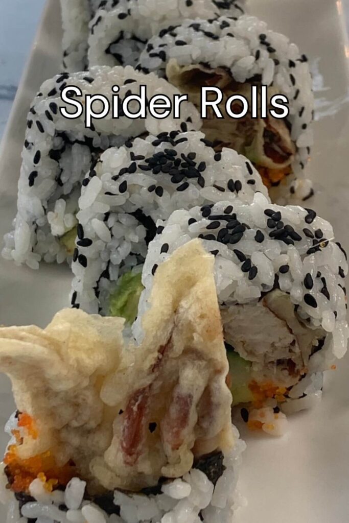 Close up vertical shot of a spider roll arranged on a white sushi plate and garnished with black sesame seeds.