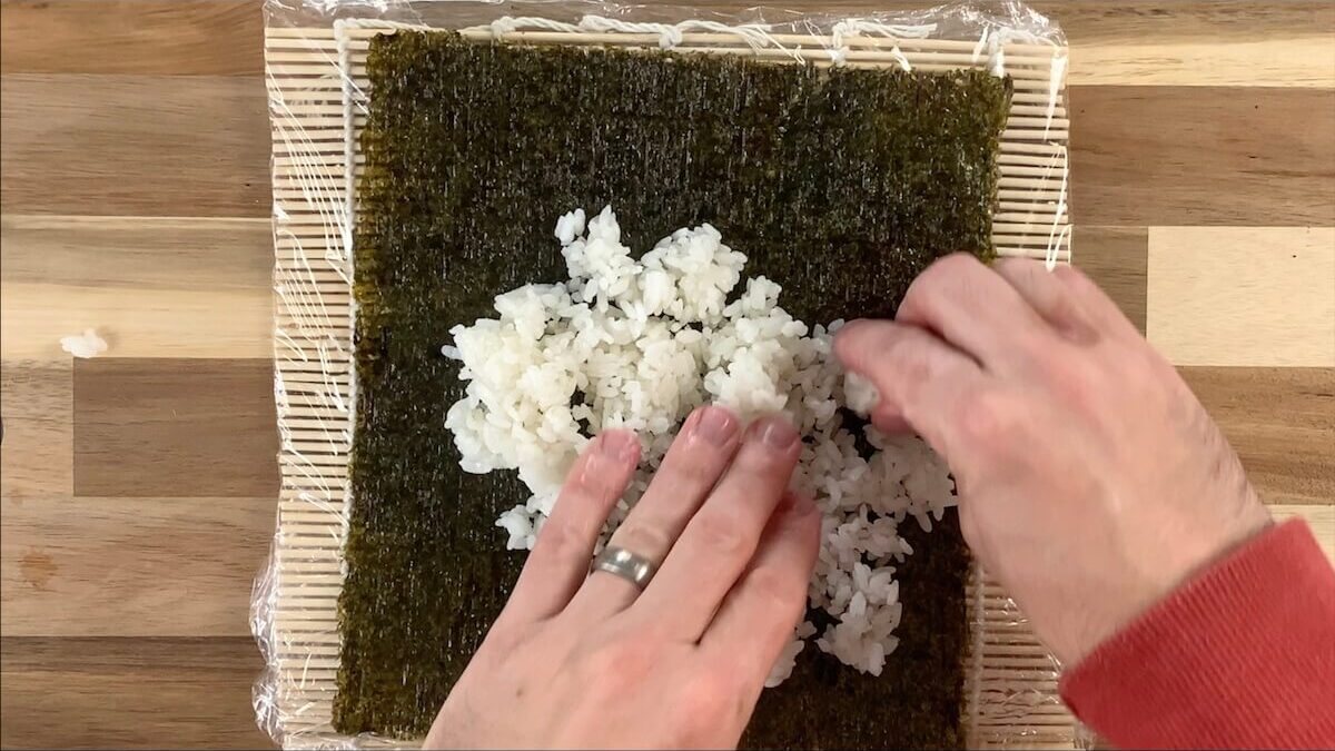 The first step in assembling your spider roll is to spread sushi rice onto your nori sheet. 