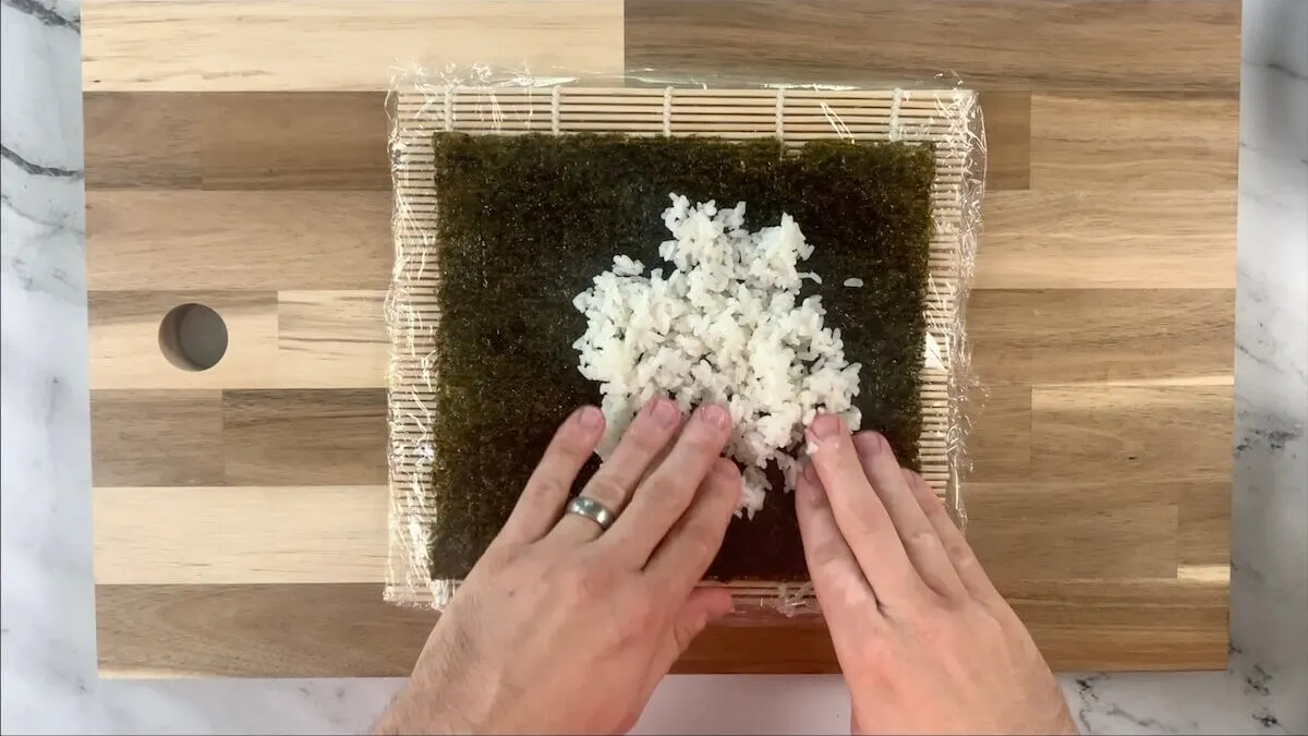 Press rice onto the nori sheet for the caterpillar roll. 