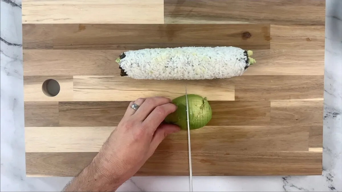 Slice the avocado to be placed over the top of the caterpillar roll. 