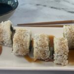 Unagi Rolls square pic on a white sushi plate with chopsticks and soy sauce in the background.
