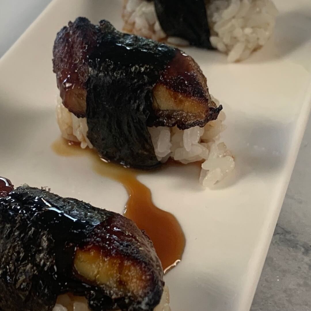 Unagi nigiri with unagi sauce on a white sushi plate