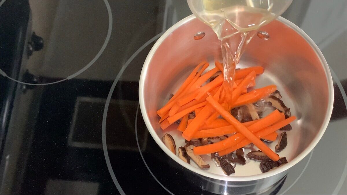 Add sliced carrots and shiitake mushrooms to a pot.