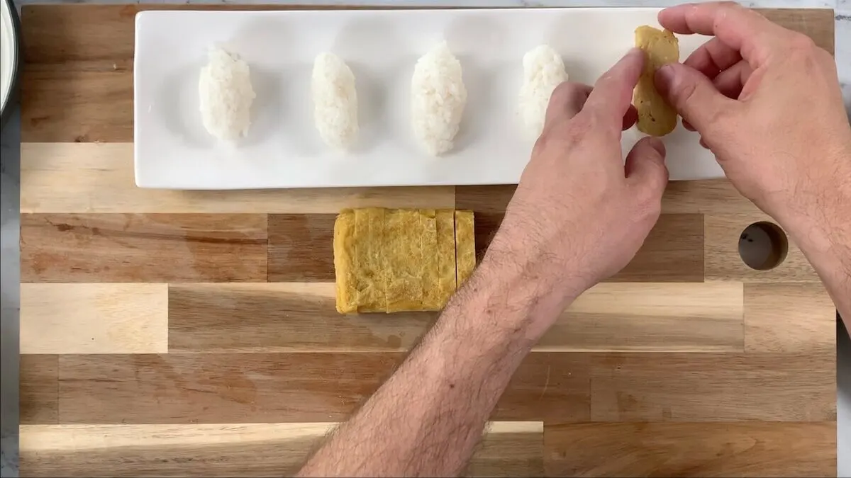 Drape the tamagoyaki over the rice ball to help form your tamago sushi.