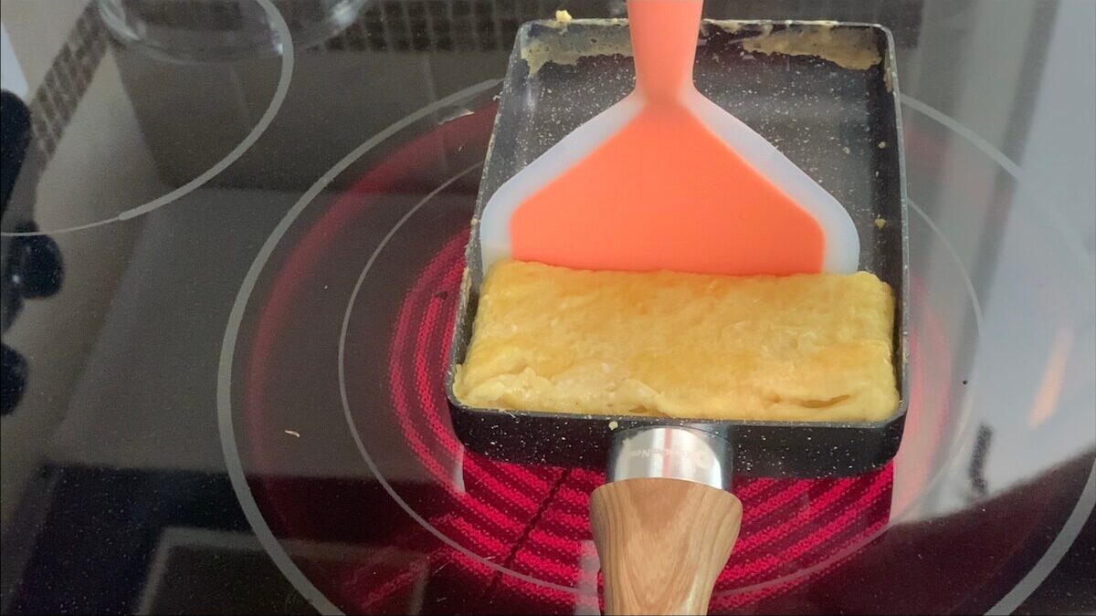 After the fourth layer of egg has been folded into the tamagoyaki, use a spatula to form into a rectangular shape