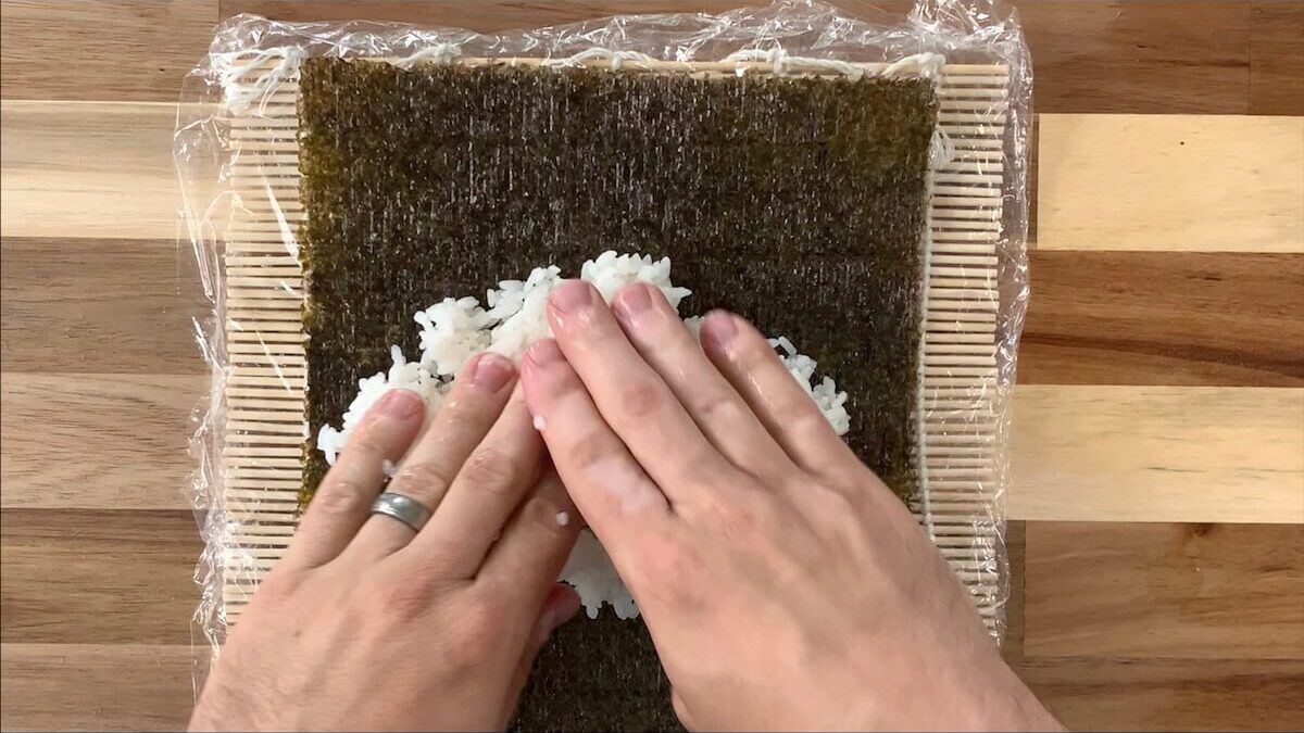 Press rice onto the nori sheet for the futomaki roll.