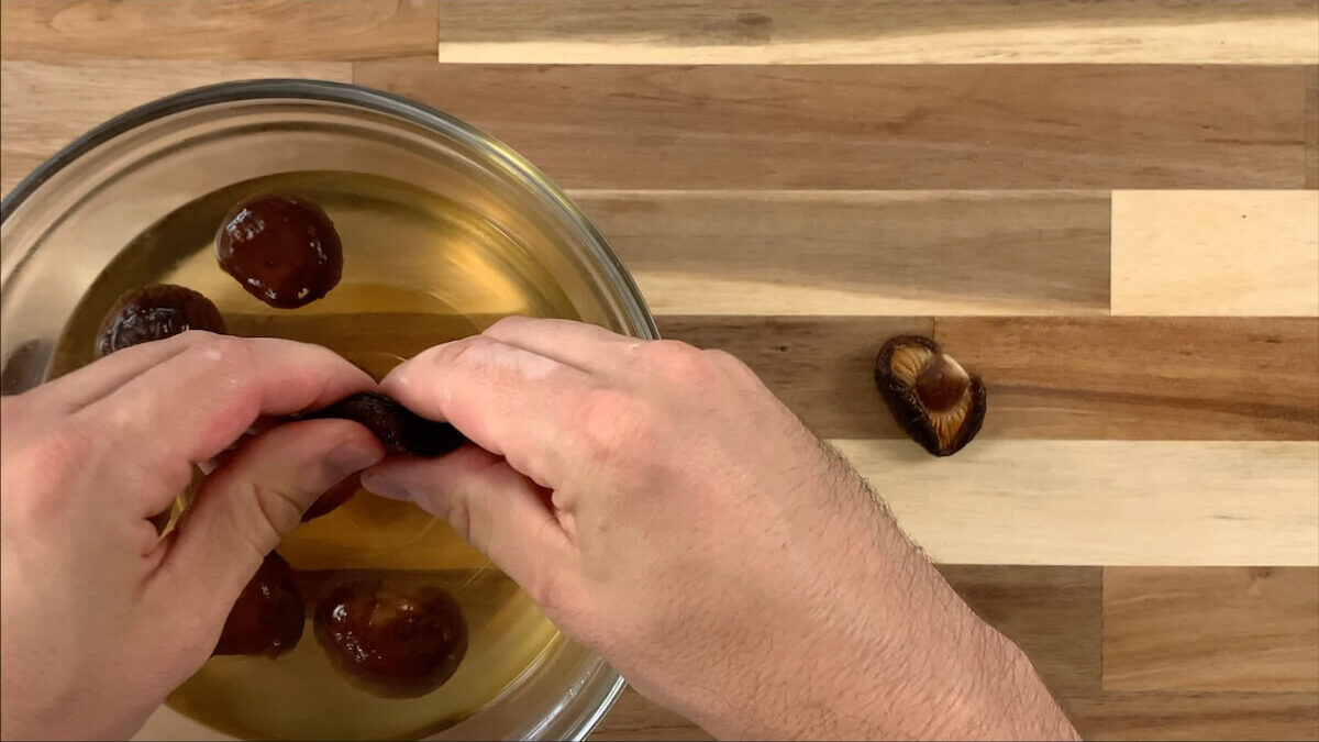 Squeeze water out of shiitake mushrooms.